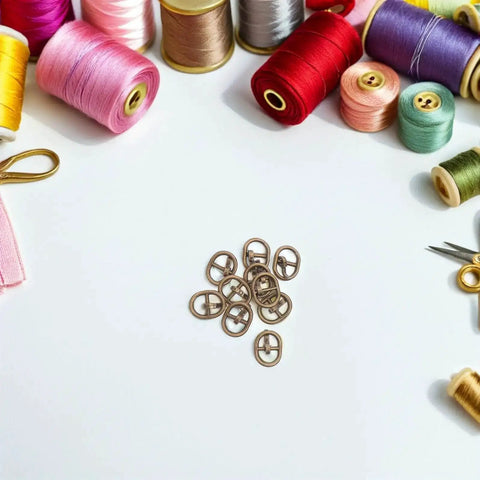 150 Piece Mini Buckle Set For Doll Clothes And Craft Projects, Small Belt Fasteners For DIY Sewing, Alloy Buckles In Silver, Gunmetal, And Antique Copper Colors For Model Miniatures And Craft Accessories surrounded by colorful threads.