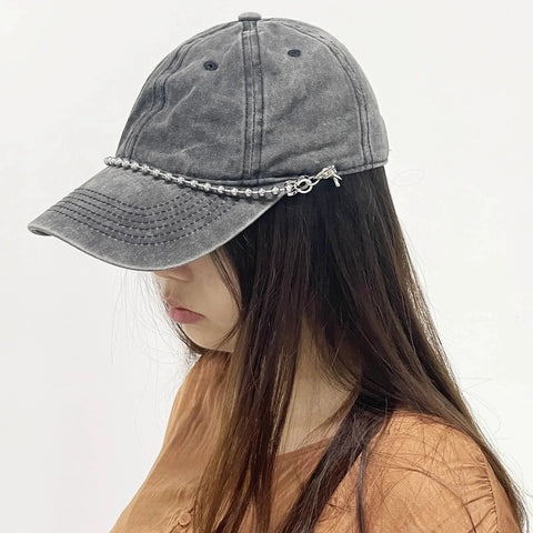 Woman wearing a mesh baseball cap with detachable pearl hat chain, featuring metal beads and lobster claw clasp, side view