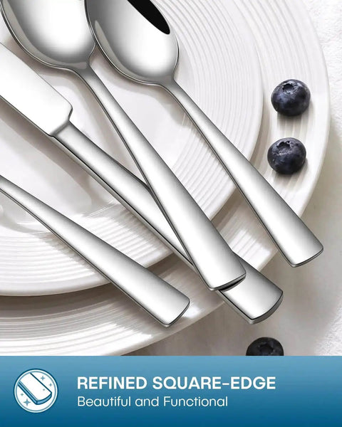 Close-up of 20 Piece Silverware Set for four with knives, forks, and spoons, mirror polished, on a white plate with blueberries