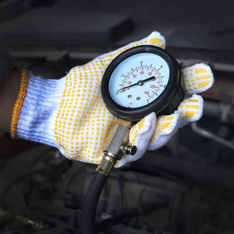 Gloved hand holding an Oil Pressure Tester Kit 0 To 140 PSI With Heavy Duty Steel Gauge Rubberized Case, used for engine diagnostics.