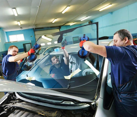 Two workers using Heavy Duty Vacuum Suction Cup Lifter 330lb for glass installation on car windshield in repair shop.