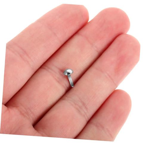 Close-up of a single iron brad with double legs in a hand, part of a "100 Piece Iron Brads With Double Leg Pins For Puppet Craft, Scrapbooking, Doll Making, Shadow Puppet Accessories, Paper Fasteners For Movable Joints And Easy Pro DIY Projects" set.