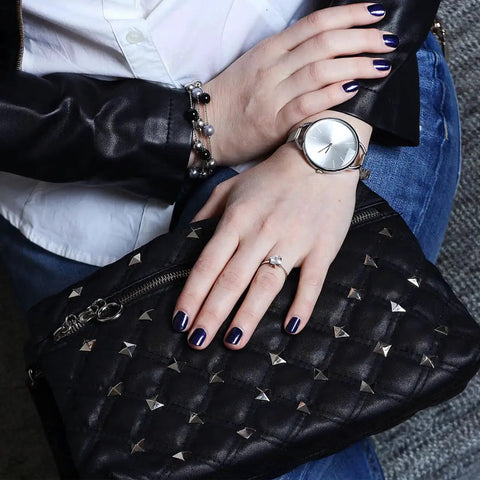 Close-up of hands holding a black clutch adorned with Silver Pyramid Spike Flatback Studs 200Pcs For Clothing Belts Leathercraft.