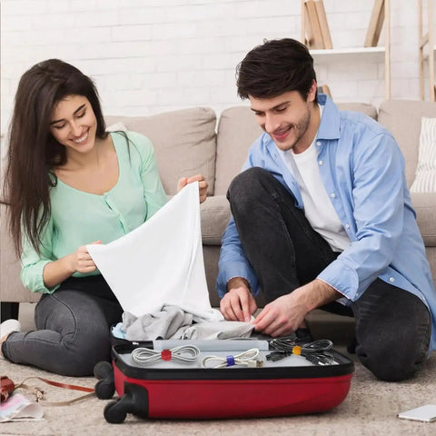 Couple using 102 Piece Reusable Hook And Loop Cable Ties Set to organize cables in a suitcase for travel.