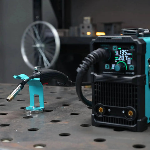 Sturdy Magnetic MIG Welding Torch Holder With Anti Rust Coating And Smooth Electroplated Finish Boss Magnetic Base For Quick Attachment And Hands Free Torch Positioning Totally Handy For MIG Welders Bestarc on metal surface next to welding machine.