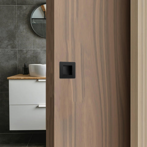 Installed Two And Three Quarters Inch Recessed Finger Flush Pocket Door Pulls in matte black stainless steel on wood door.
