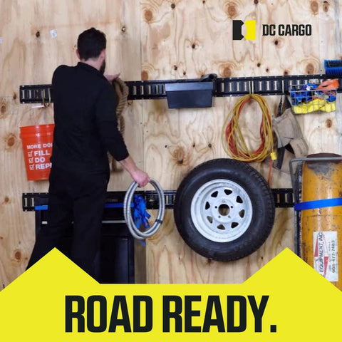 Man organizing trailer with DC Cargo gear for road readiness and transport security