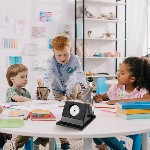 Children gathered around a table with a 58mm Button Maker Circle Cutter Punch For Badges And DIY Crafts, sturdy metal base visible.