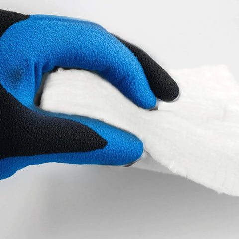 White ceramic fiber blanket insulation held by a blue and black gloved hand