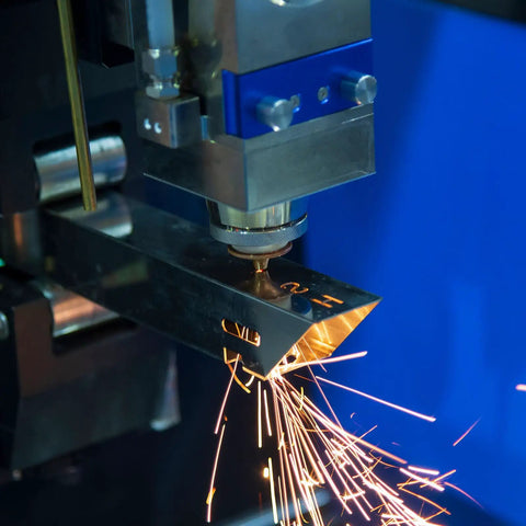 Industrial laser cutting machine sparks in a workshop.