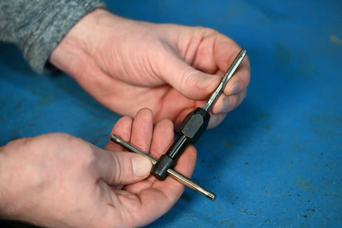 Hand holding T-Handle Tap Wrench For Quarter To Half Inch Taps Steel Construction Precise Control Easy Install And Firm Grip
