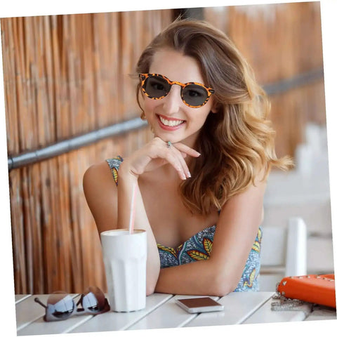 Woman wearing outdoor sports sunglasses with UV protective lenses and ergonomic frame, sitting at a table outdoors.
