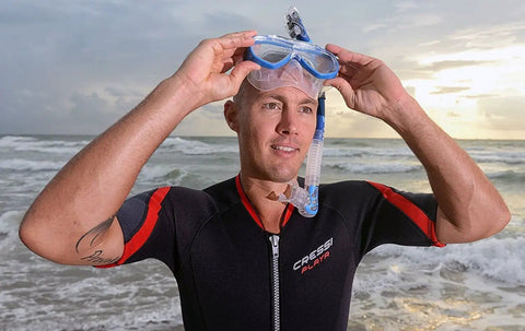 Person holding Dry Top Snorkel With Instant Float Closure No Fuss Anti Splash Snorkel Gear in black and blue finish on the beach.