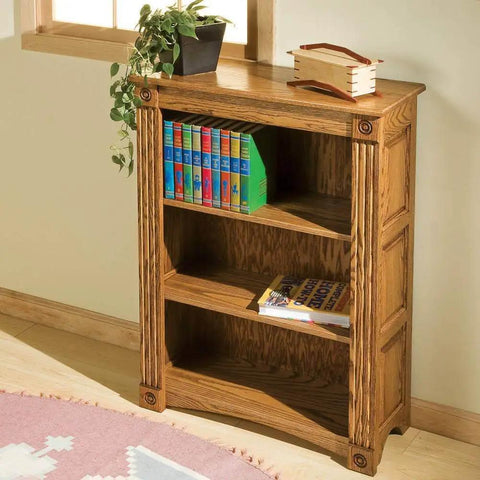Wooden bookshelf in room with books and decor on top, located near window on light wood flooring.