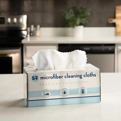 50 Pack Microfiber Cleaning Cloths 11.8x11.8 White 190gsm For Home And Auto in a storage box on a kitchen counter.