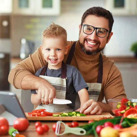Real Kitchen Skills For Little Chefs 13 Piece Toddler Knife Set With Wooden And Plastic Knives Includes 4 Serrated Edges Crinkle Cutter Y Peeler Cutting Boards Safe Kid Friendly Kitchen Tools For First Time Helpers displayed in use by adult and child in kitchen