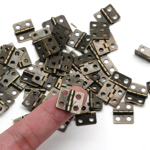Retro Dope Mini Copper Hinges For Wooden Jewelry Box With 50 Hinges And 200 Replacement Screws, shown in pile, finger for scale.