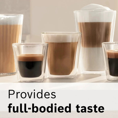 Set of five clear glass coffee cups on a light kitchen counter with layered espresso drinks and milk foam.