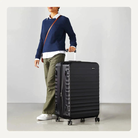Person holding Big 30 Inch Hardside Checked Luggage With Four Spinner Wheels Scratch Resistant Shell Expandable Up To 15 Percent