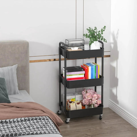 3 Tier Plastic Rolling Utility Cart With Handle For Office Kitchen And Living Room next to a bed, multifunctional storage trolley with books and decor items.