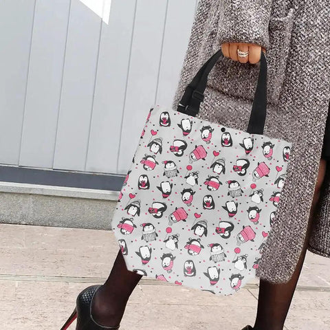 Person holding a cute penguin-patterned tote bag with black handles