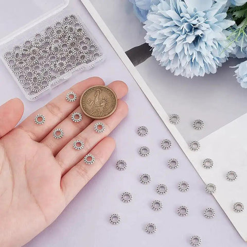 Silver Flower Spacer Beads 100 Pcs Daisy Rondelle Beads For DIY Jewelry Making shown with coin for scale.