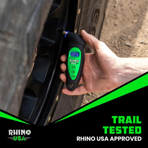 Rhino USA digital tire pressure gauge with green backlit LCD display and blue lighted nozzle used on car tire.