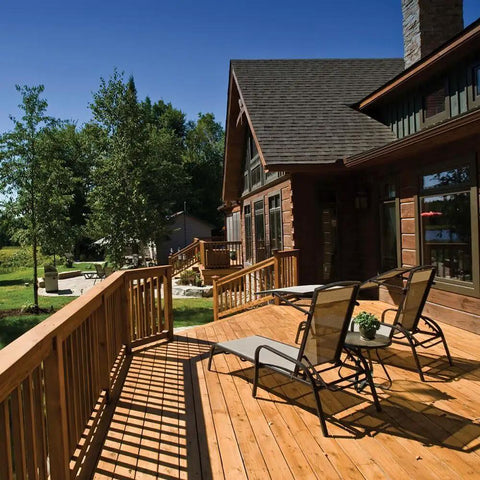 Wooden deck with chairs outside a house surrounded by trees, showcasing the use of durable outdoor materials.
