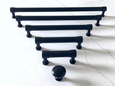 Set of matte black cabinet pull handles and knobs, including Matte Black Cabinet Pull Handle 2.75 Inch Centers 70 Mm Center to Center Drawer Knob Pull for Kitchen Cabinets Dresser Pulls Hardware Includes 1 Inch Screws Easy Mount DIY Friendly Durable Metal Finish, displayed on a marble surface.