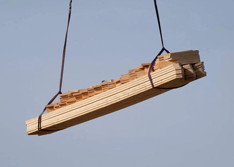 Side view of a bundle of light wooden planks strapped with purple lifting slings