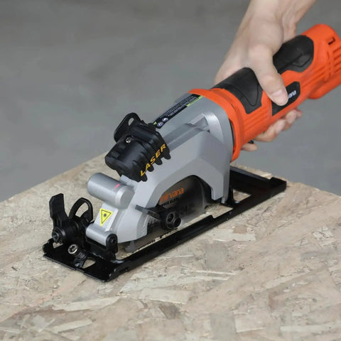 Hand operating Powerful 4 Amp Mini Circular Saw With Laser Guide And Vacuum Adapter on wood surface, showing compact design and components.