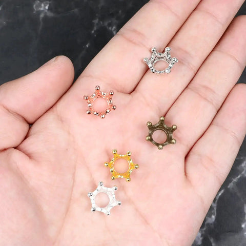 60 Piece Crown Charms Set For Jewelry Making With Six Vintage Colors 3D Alloy Crown Beads displayed on a hand