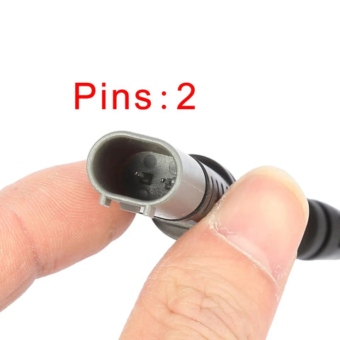 Close-up of gray two-pin automotive brake pad wear-sensor connector held between fingers