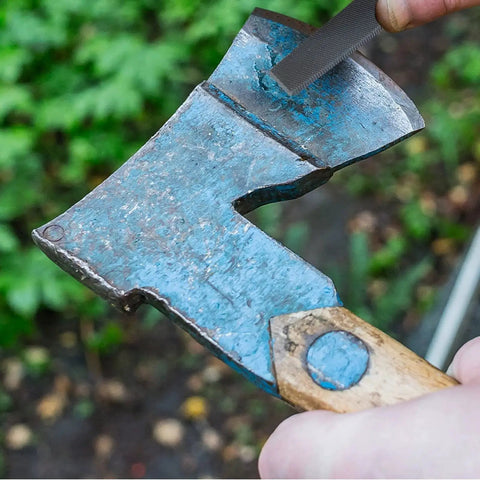 Flat 6 Inch Hand File With Double Cut Teeth And Single Cut Edge Made From High Carbon Steel in use sharpening a blue axe head.