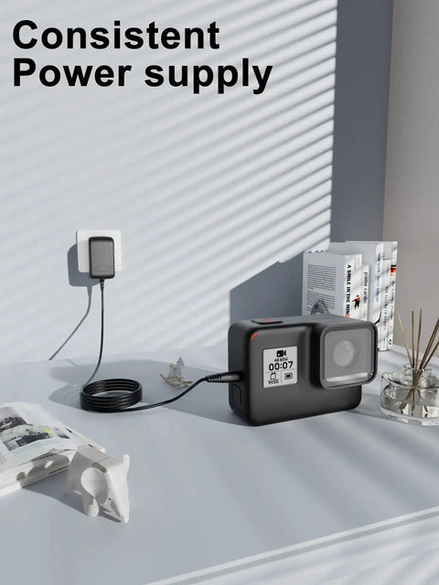 Action camera charging on table with 24V AC DC Power Adapter Charger connected to wall socket