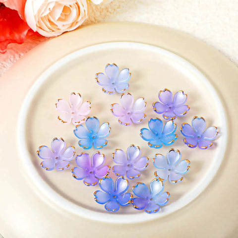 100 Pcs Cherry Blossom Acrylic Flower Beads For Jewelry Making And Bracelet Charms, Pink And Blue Gradient With Gold Edge Petal Mini Spacer Beads, Super Cute Floral Beads Set For DIY Jewelry Projects displayed on a beige plate