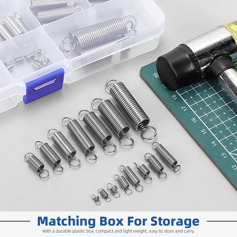 Stainless steel extension springs with double hooks, 96-piece set in 15 sizes, laid out beside a plastic storage box and cutting mat