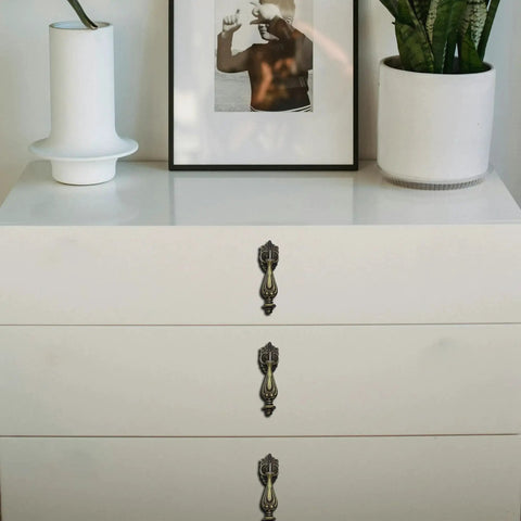 White dresser with Antique Brass Drop Pull Handles 4 Pack Featuring Ornate Pendant Drawer Knobs With European Scrollwork Base.