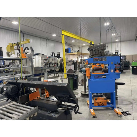 Workshop with various industrial machines, featuring the 8 Inch Sheet Metal Brake For One Quarter Inch Thick Steel, MP4110 Model in orange.