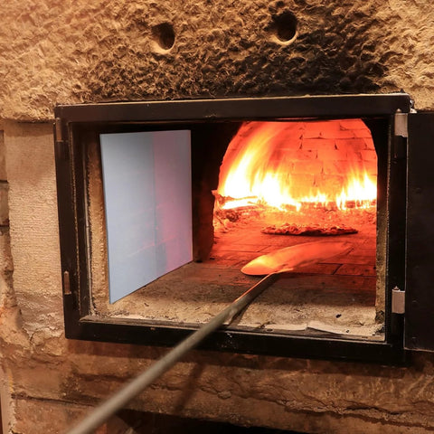 High temperature gasket sheet inside furnace; blue ceramic fiber insulation panel on left, glowing fire, shovel in front.
