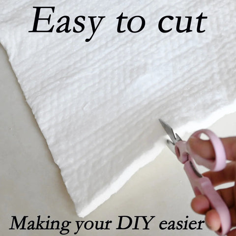 White ceramic fiber blanket insulation being cut with pink-handled scissors