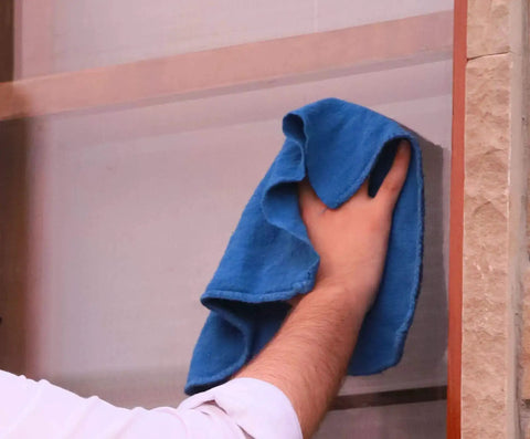 Person cleaning window with blue 150 Pack Cotton Shop Towels 14 By 12 Inches Absorbent Rags For Auto Shops Garage Home And Industry