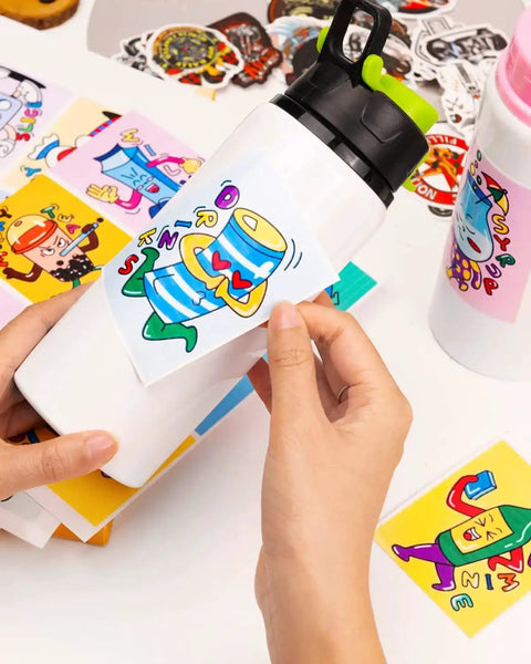 Hands applying sticker on water bottle using Premium Printable Vinyl Sticker Paper For DIY Crafts QYH 50 Sheets Glossy White Quick Drying