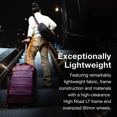 Traveler with Ozone 2-Wheel Carry-On Luggage With Oversized Wheels And Telescoping Handle From Osprey on escalator