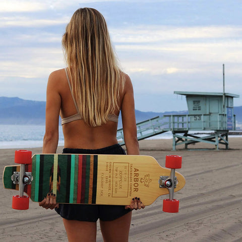 608-RS ball bearings, 10-pack; person seen from behind holding a striped longboard on the beach
