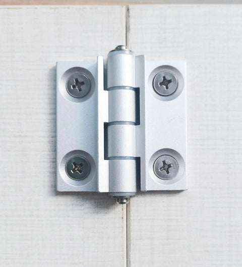 Installed torque position control hinge, aluminum alloy, white finish, mounted on light wood boards.