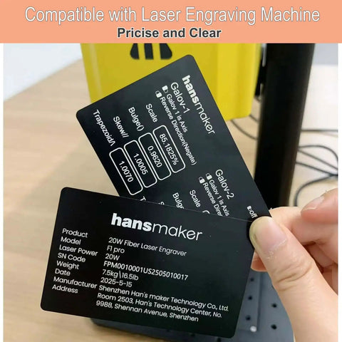 Person holding shiny business cards with technical specifications in front of yellow laser engraver.