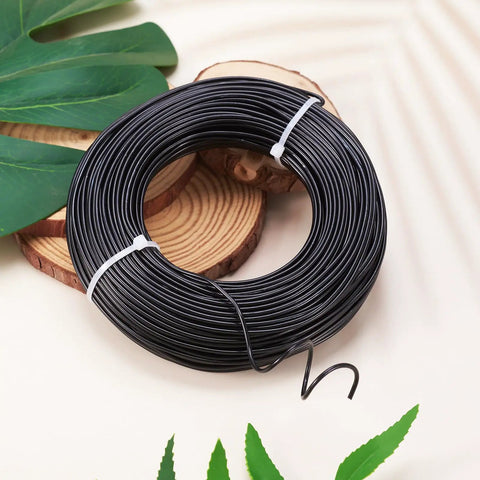 Black Aluminum Craft Wire 180 Feet 12 Gauge Bendable Wire For DIY Beading Jewelry Making, flexible spool on a wooden surface.