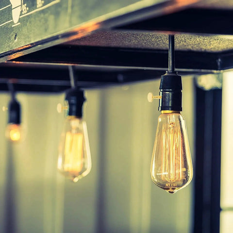 Hanging light bulbs with visible filaments under a metal frame, focus on modern industrial lighting design.