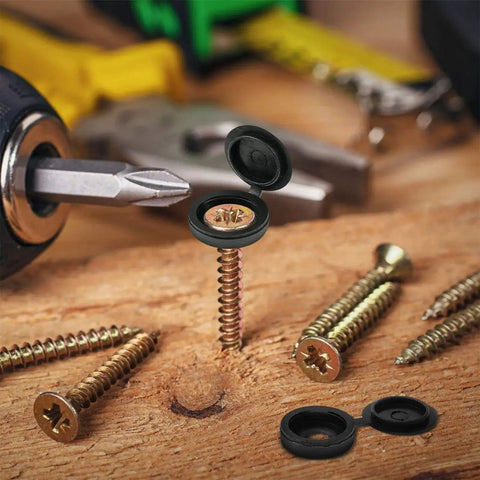 Close-up of hinged plastic screw cover caps with shutter fold design in black, showing snap-on feature on wooden surface